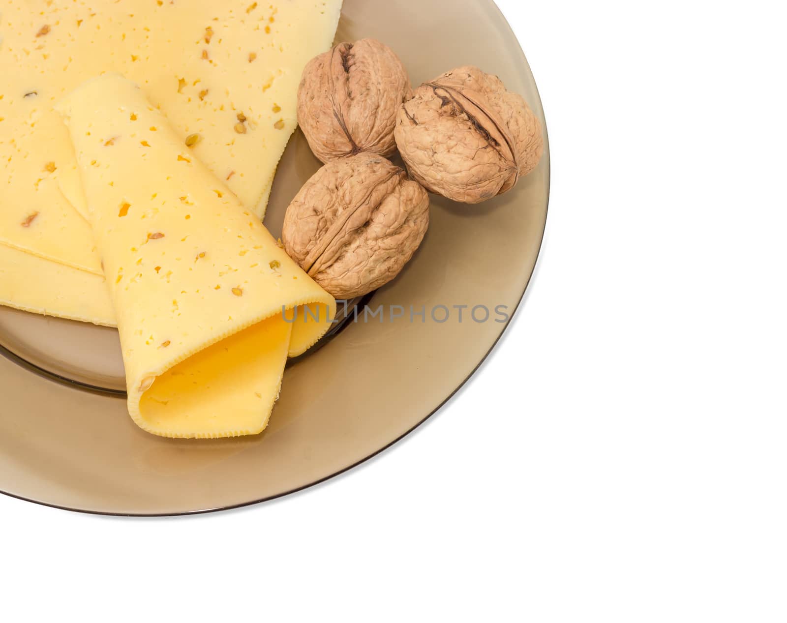 Fragment of glass dish with several slices of a semi-hard cheese made with pounded walnuts and several whole walnuts closeup on a light background
