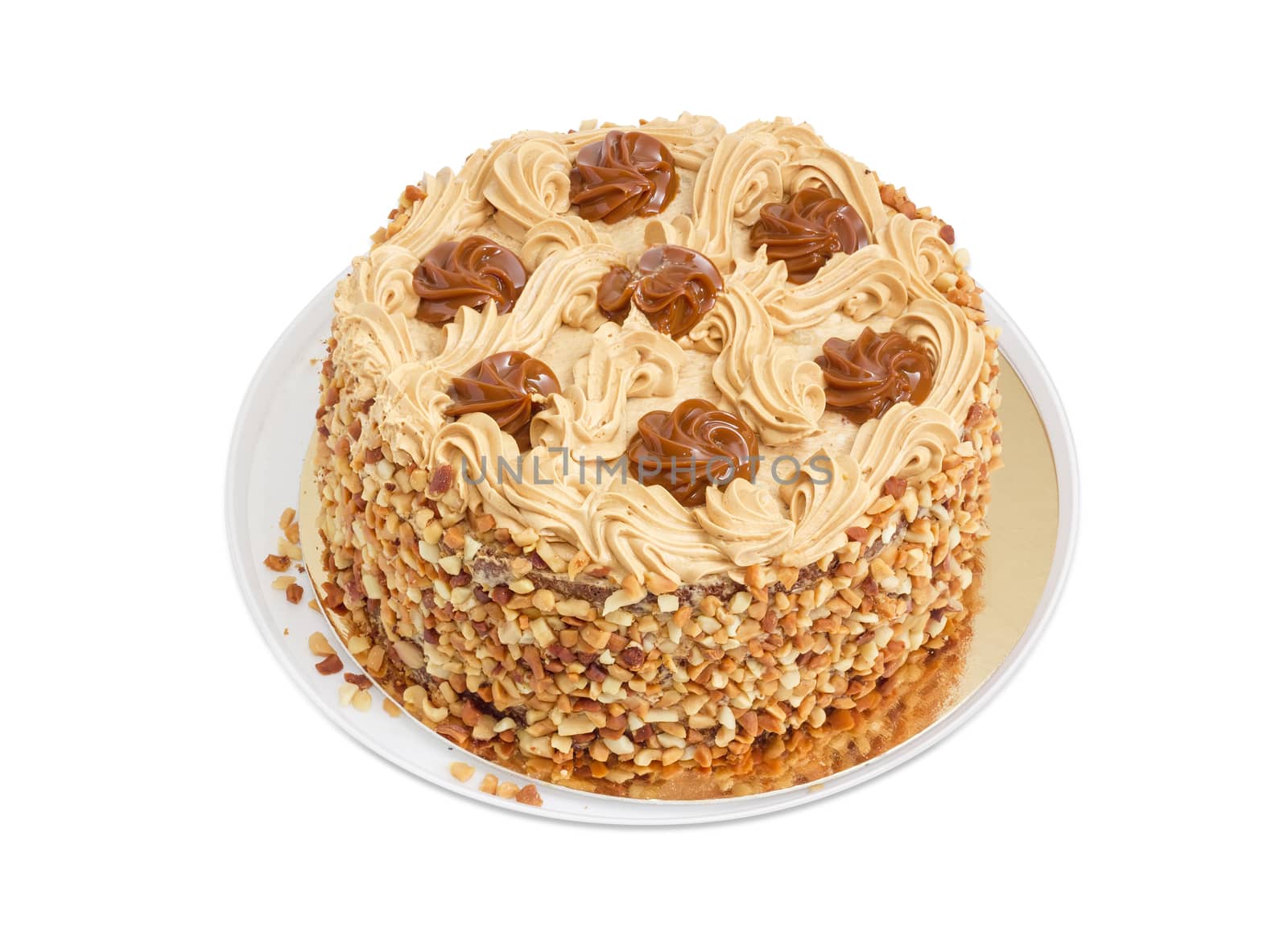 Round sponge cake, decorated with butter cream and caramelized condensed milk, sprinkled with grated nuts on a light background
