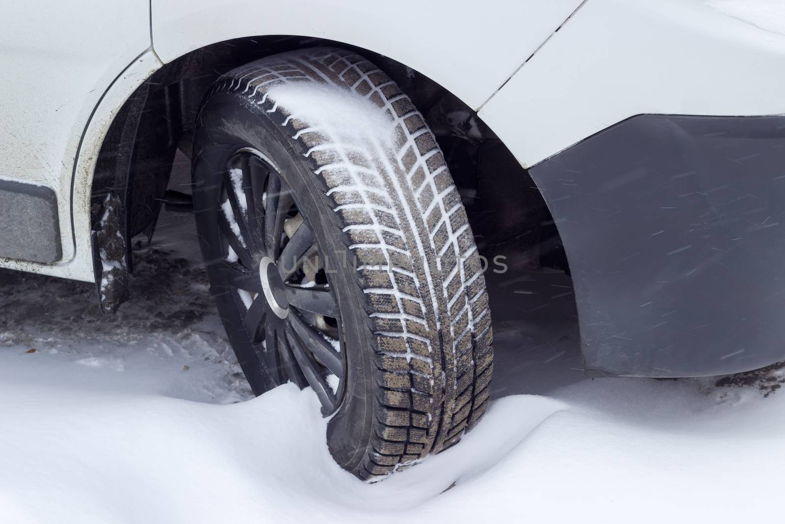 Front wheel of the car with snow tire closeup by anmbph