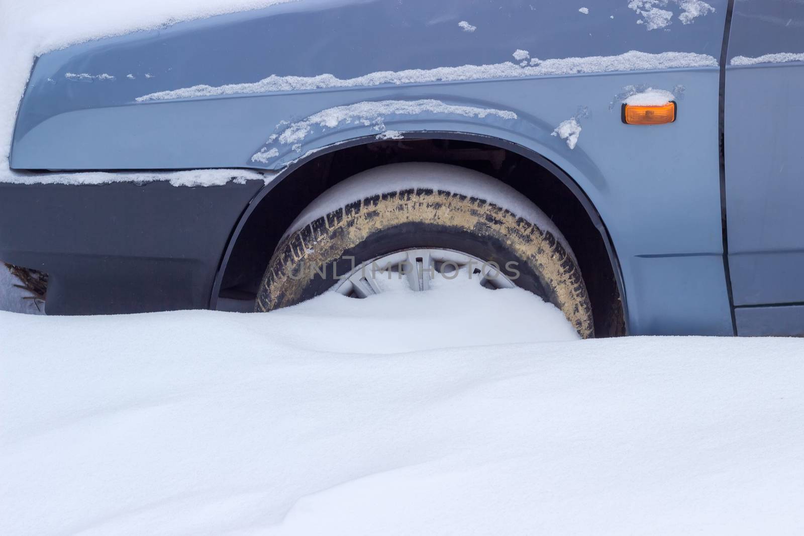 Fragment of snow covered car with wheel covered with mud by anmbph