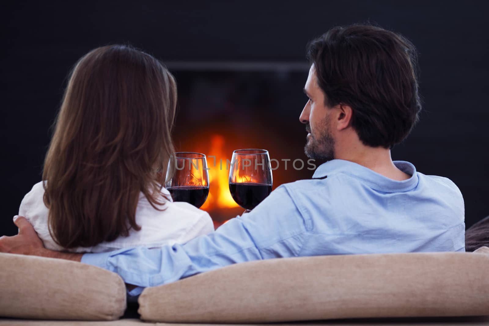 Romantic couple drinking wine at home near fireplace