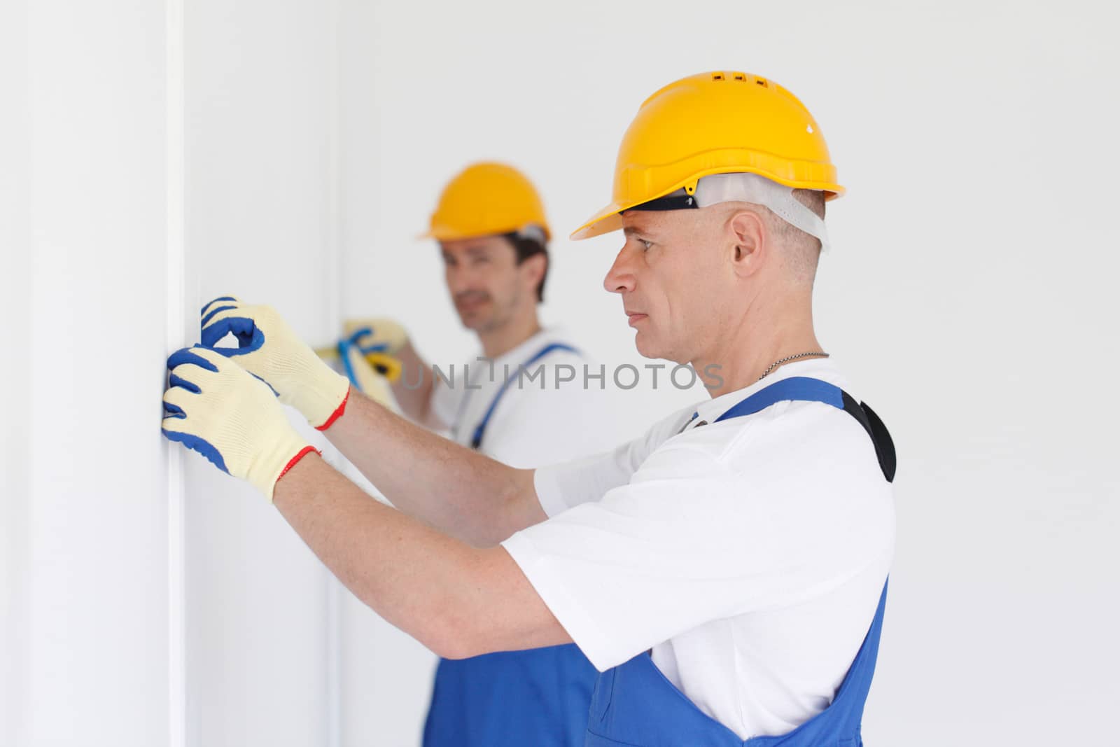 Men in uniform and hardhats measuring wall with tape