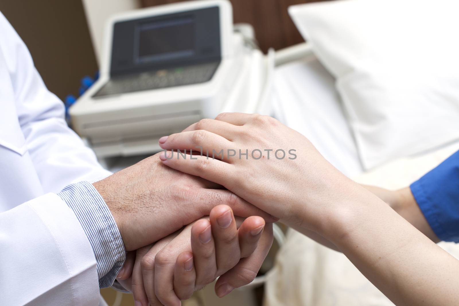 Close-up of doctor holding patient's hands in hospital.