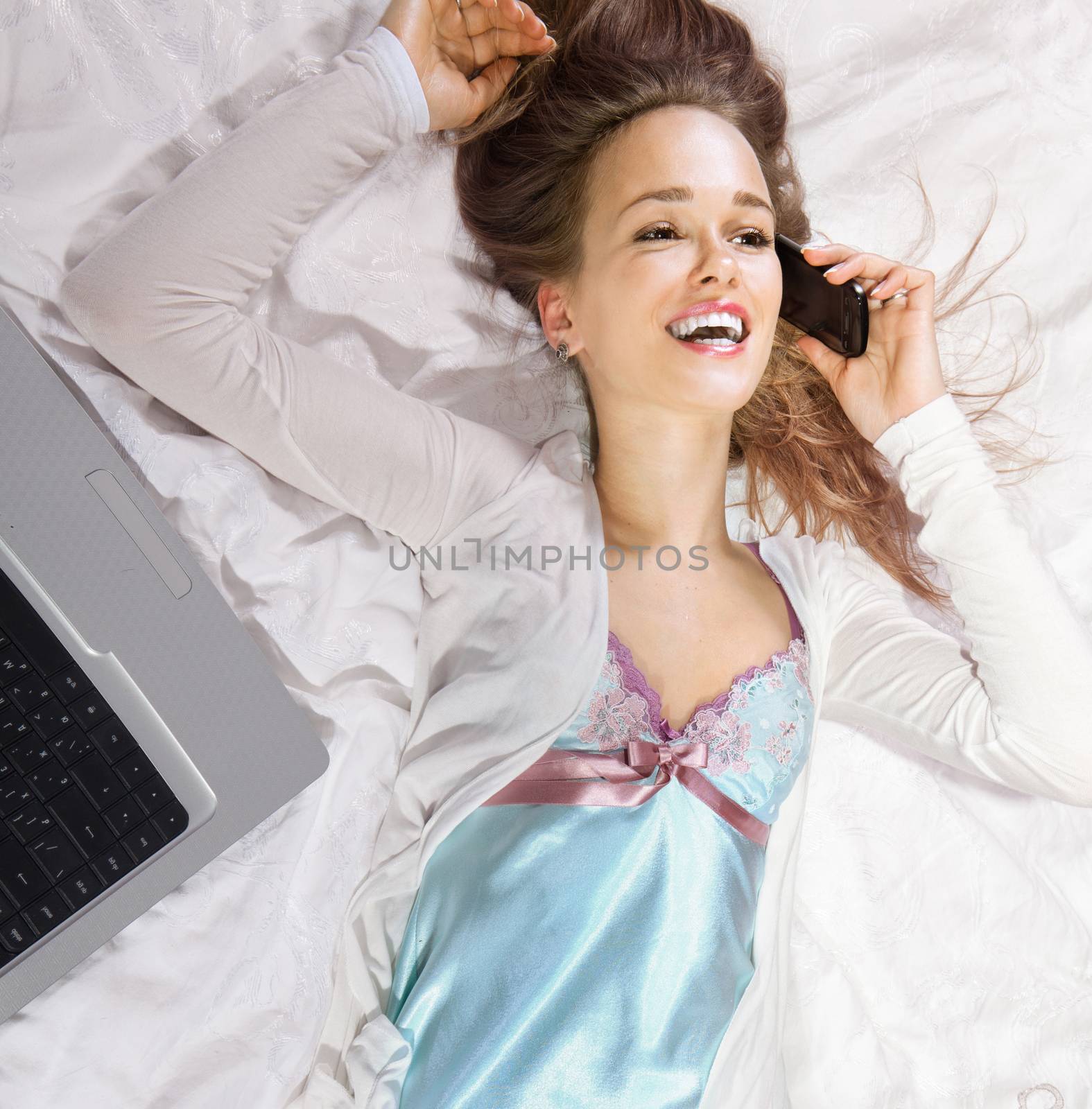 happy girl lying on the bed holding her smartphone