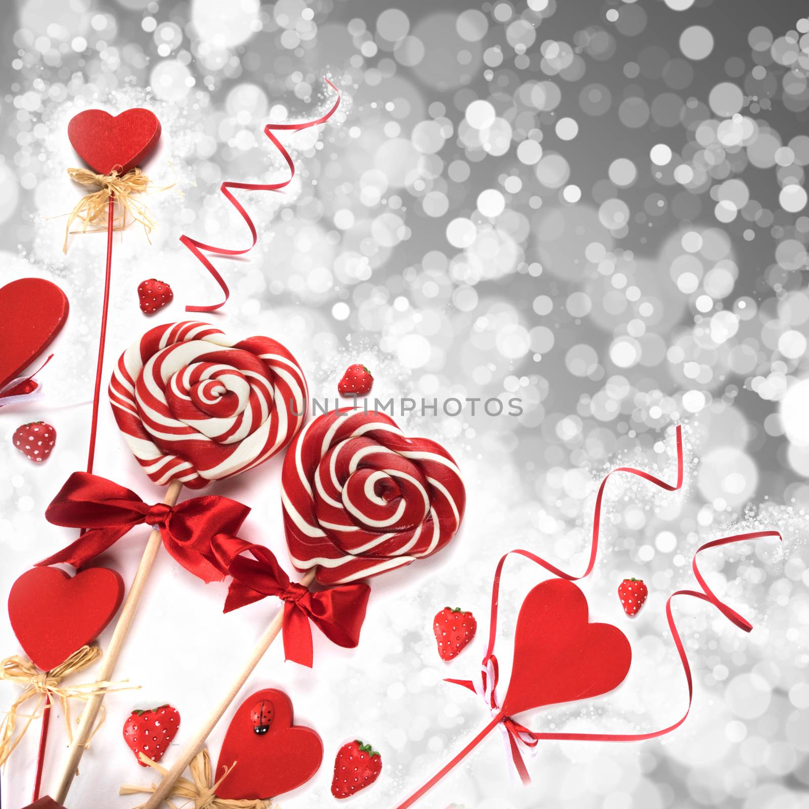 Lollipops and heart shaped decoration on silver glitter background