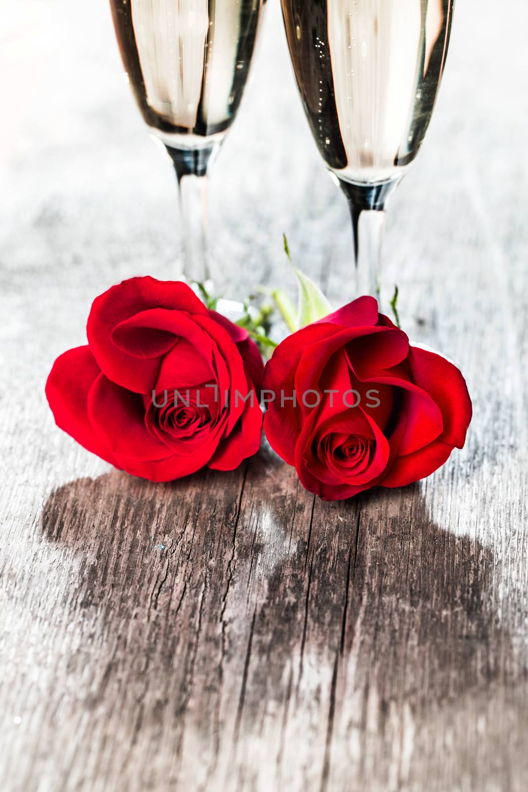 Champagne and red roses on wooden background