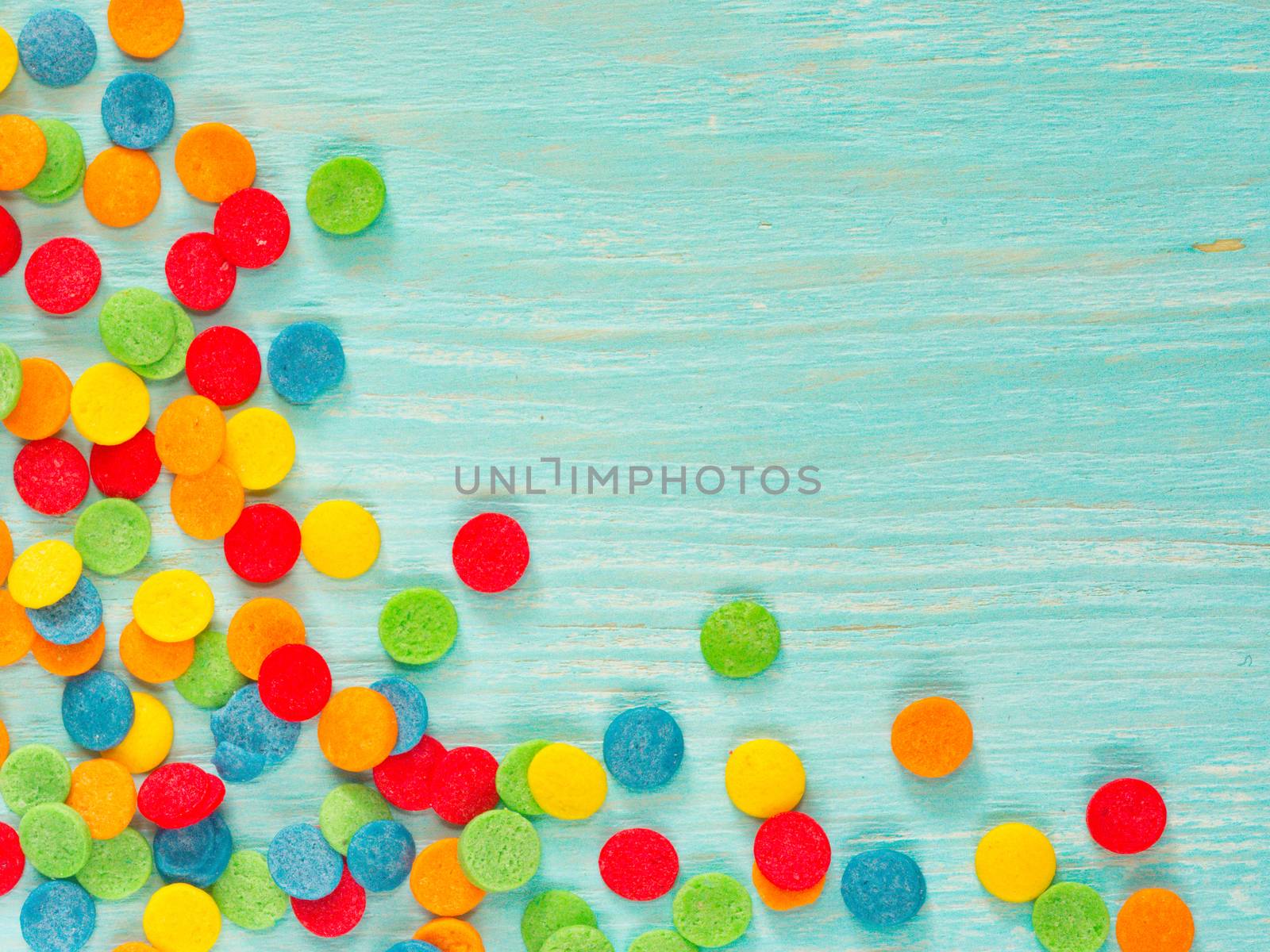Border frame of colorful sprinkles on blue background with copyspace. Top view or flat lay