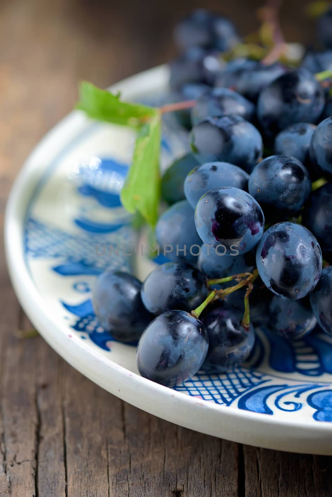 black grapes on plate on wooden table