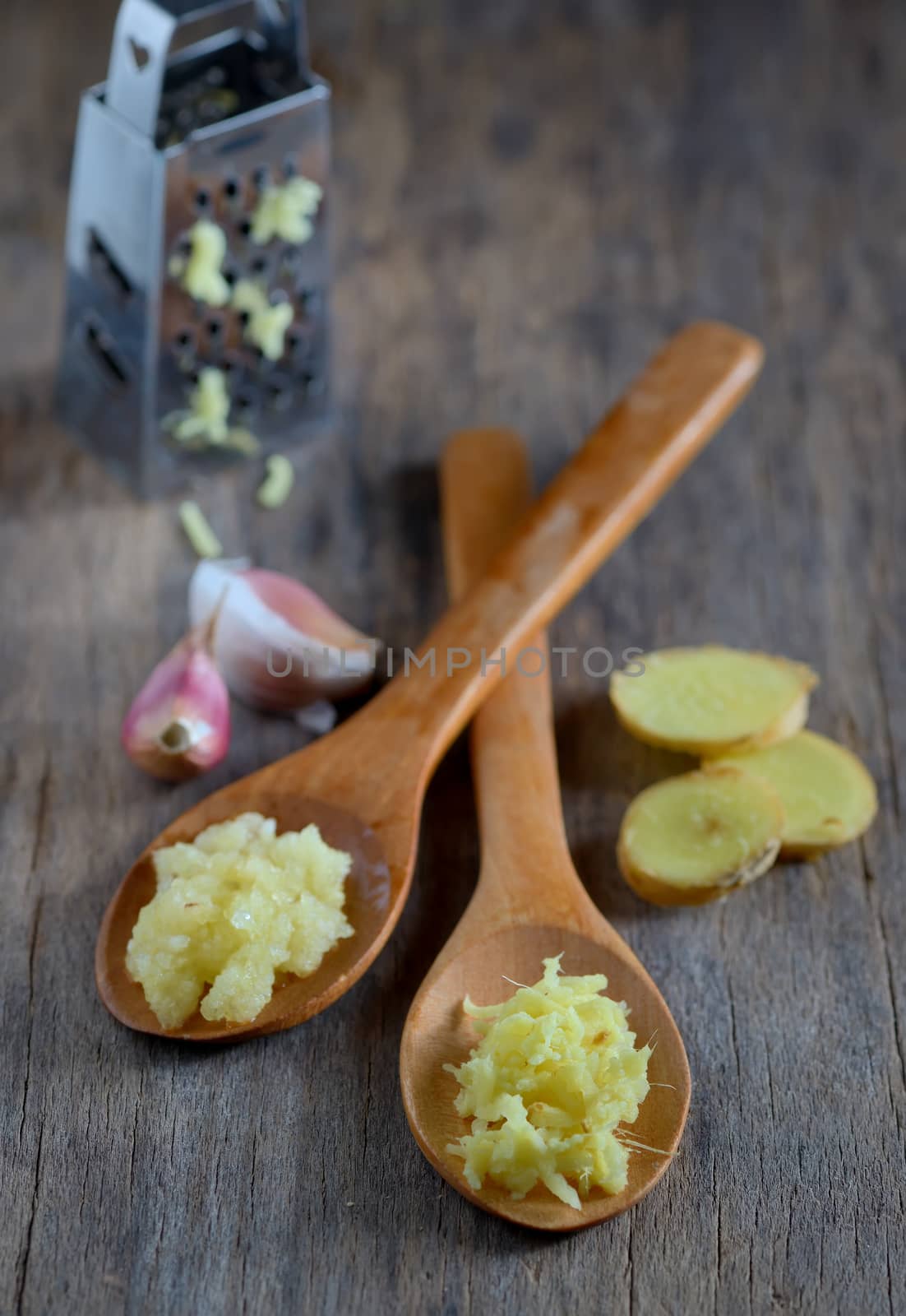 garlic and ginger in wooden spoons on wooden table