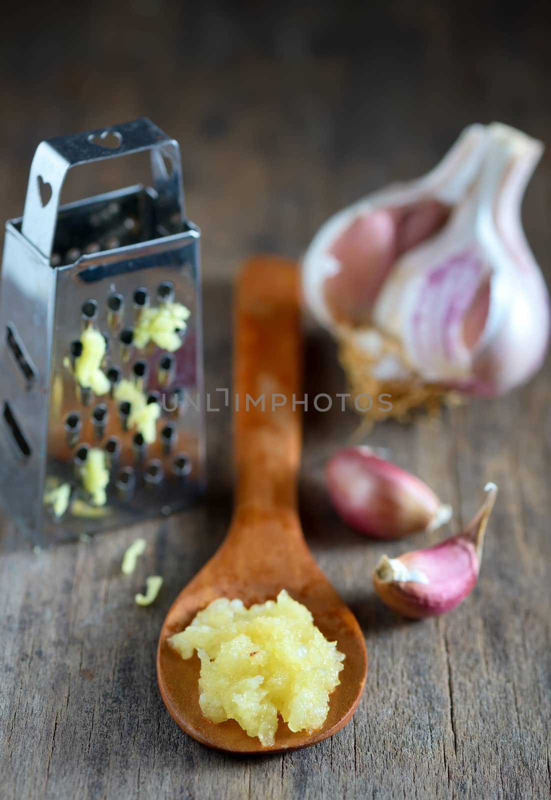 Garlic in spoon on wooden background
