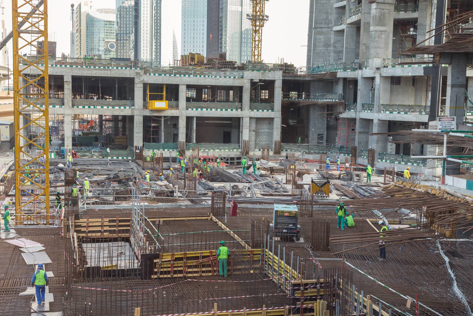 Laborers working on modern constraction site works in Dubai. Fast urban development consept.