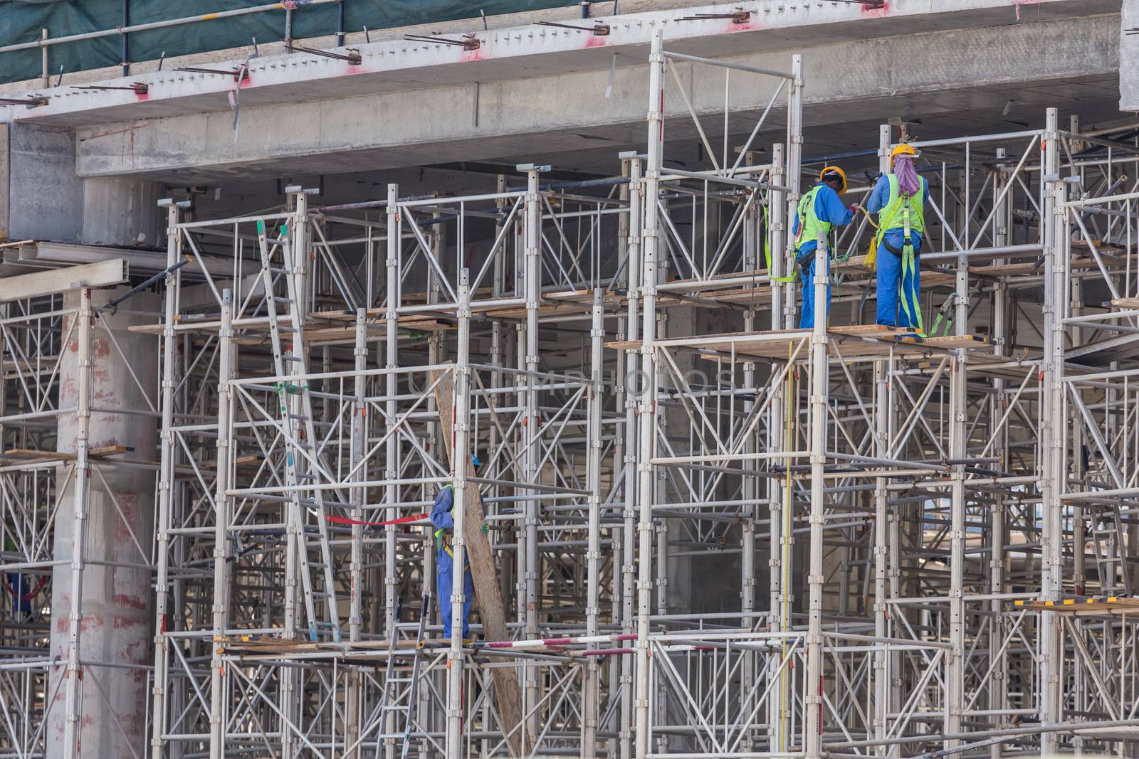 Construction site with team of construction laborers working on scaffold.