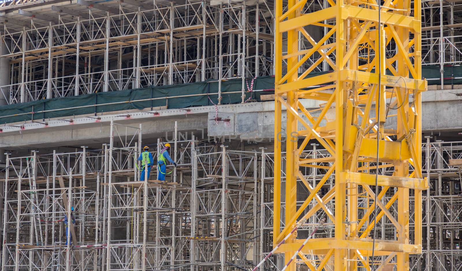 Construction site with team of construction laborers working on scaffold.