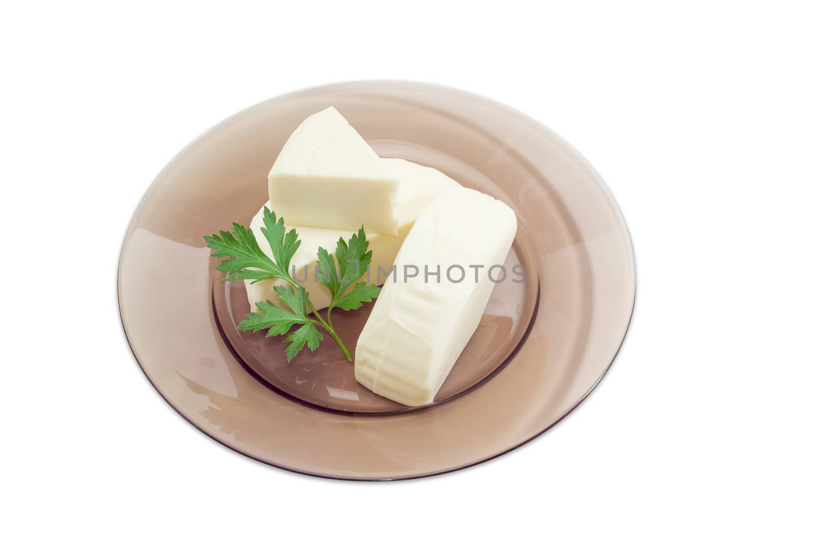 Three pieces of fresh mozzarella cheese and sprig of parsley on a dark glass dish on a light background
