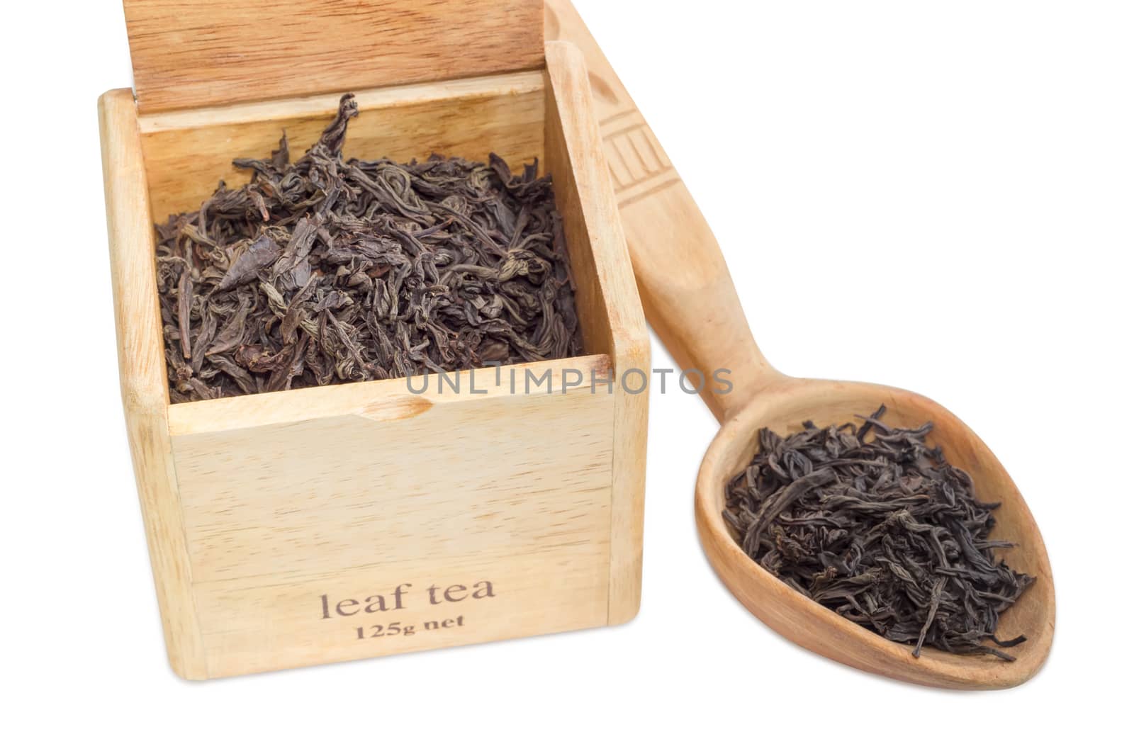 Large leaf of black tea in a wooden box and wooden spoon on a light background closeup
