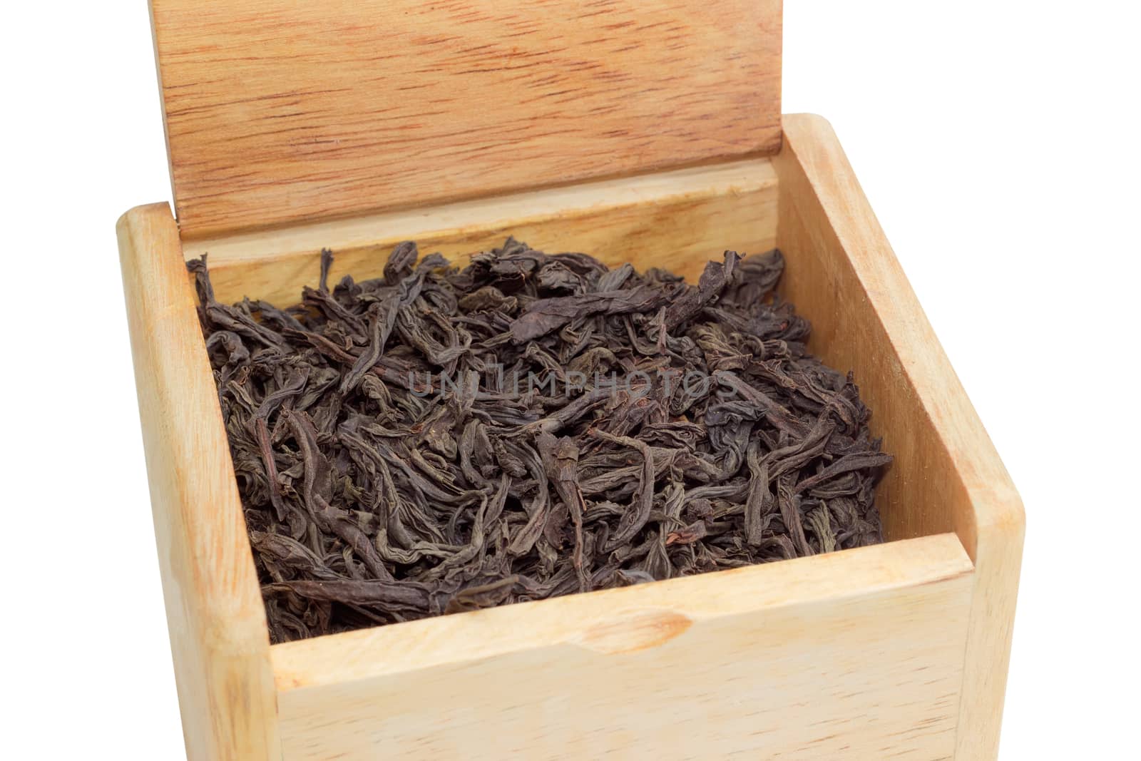 Dried large tea leaves of black tea in a wooden box on a light background closeup
