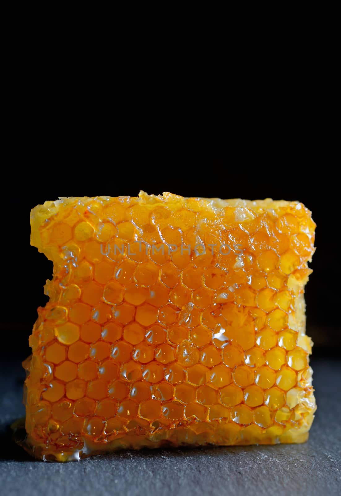 Honeycomb and honey on black plate