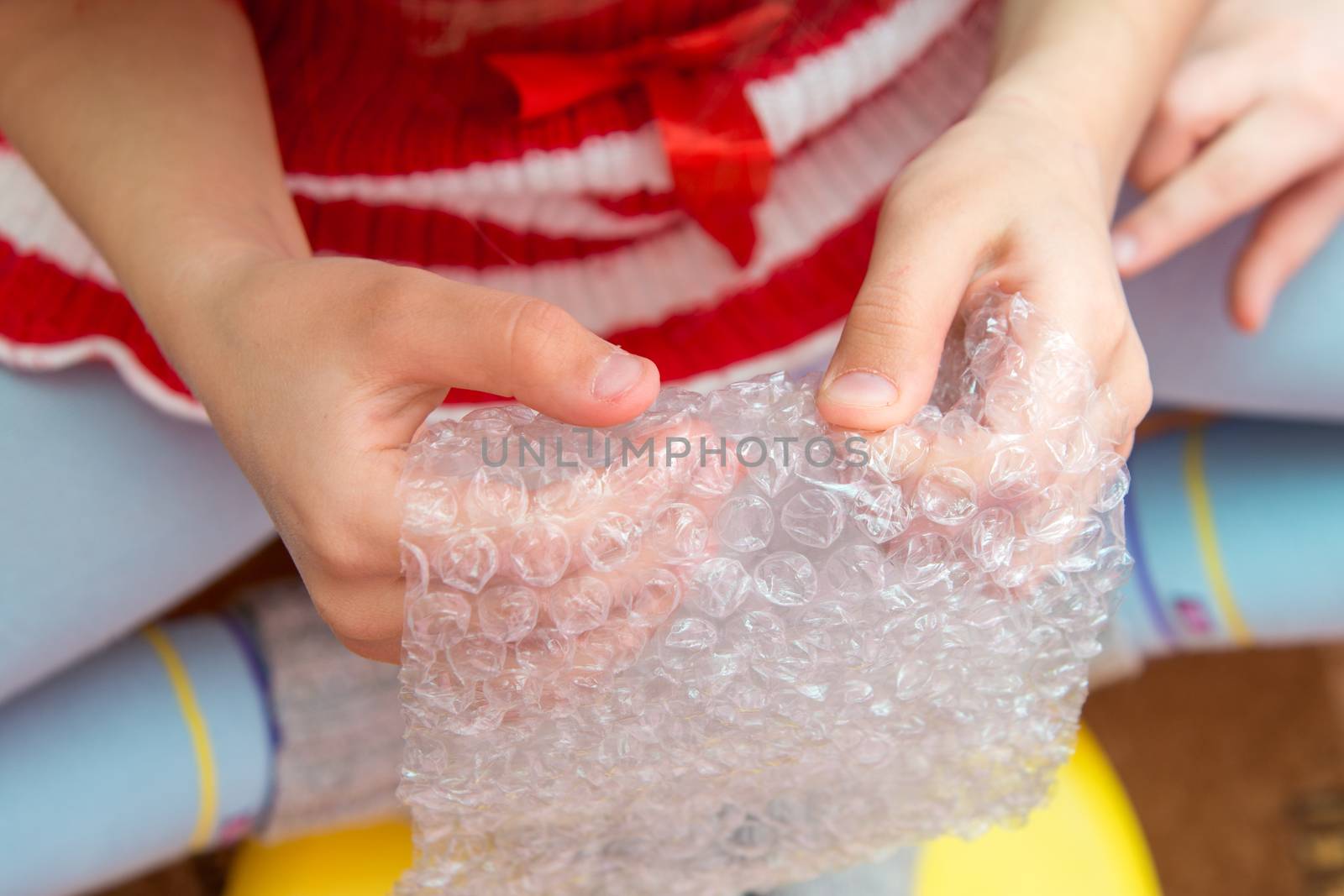 Top view of the child's hands pressing the bubbles on the packaging film