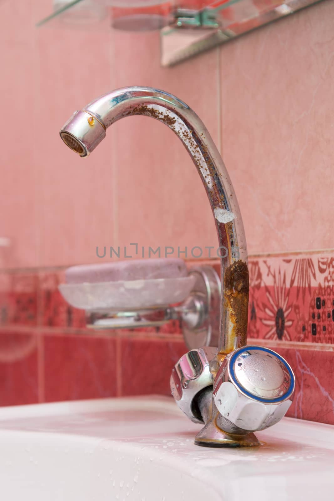 Old rusted tap on the sink in the bathroom