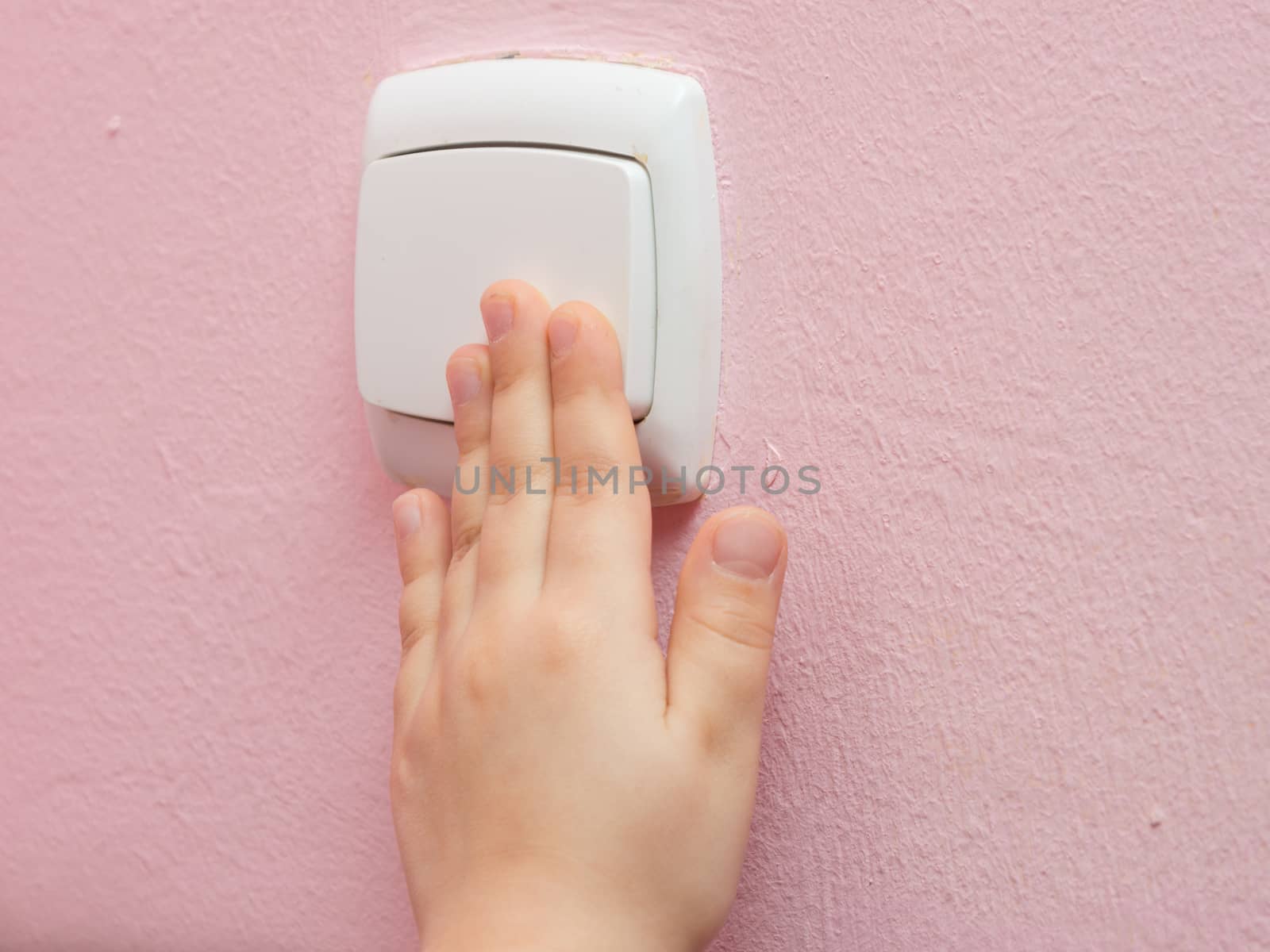 Child's hand presses the light switch, close-up