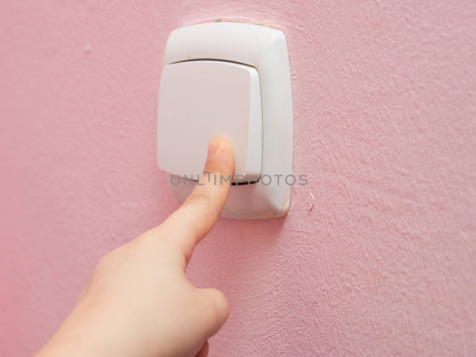 Child's hand finger presses the switch, close-up