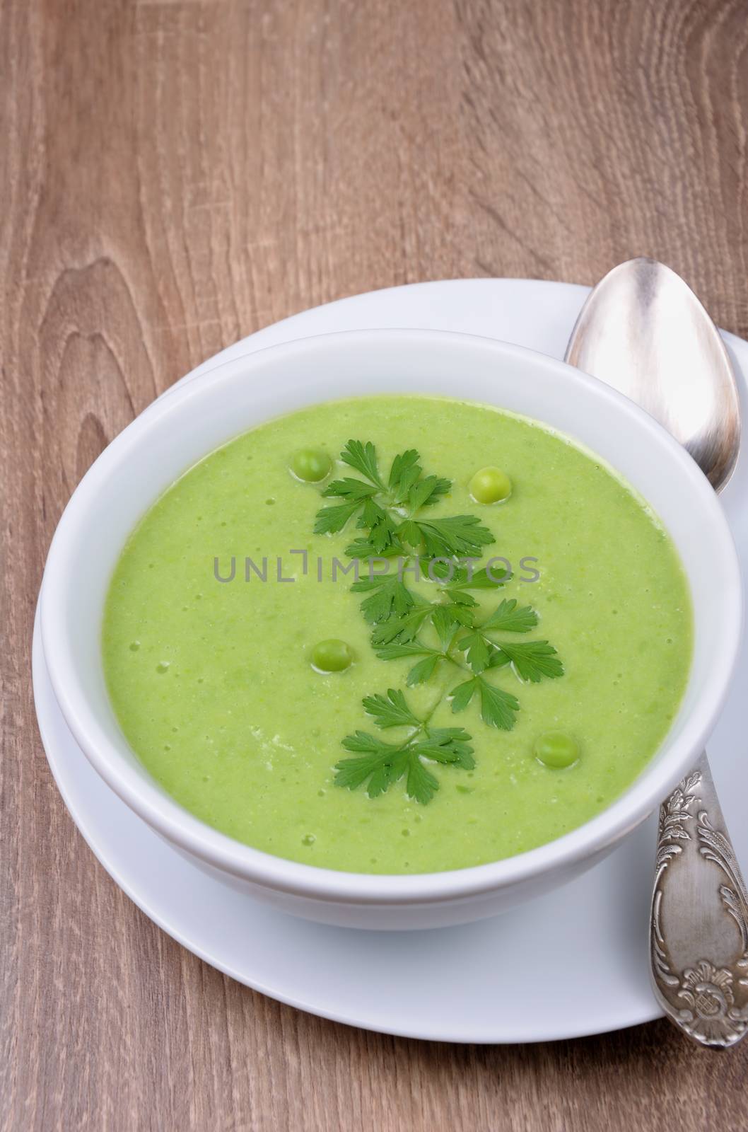 A plate of soup puree of green peas with parsley on a table