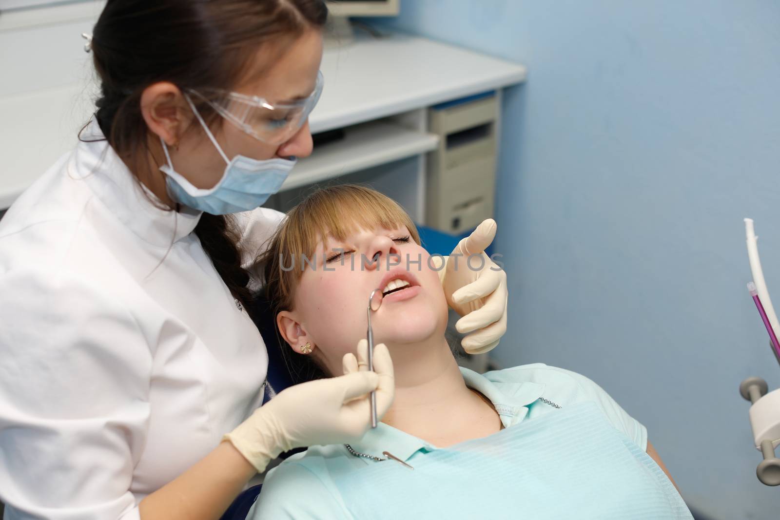 Dentist in a private office holds reception of the patient with pain. The Dentist Selects The Tool And Starts Examination Of The Teeth.