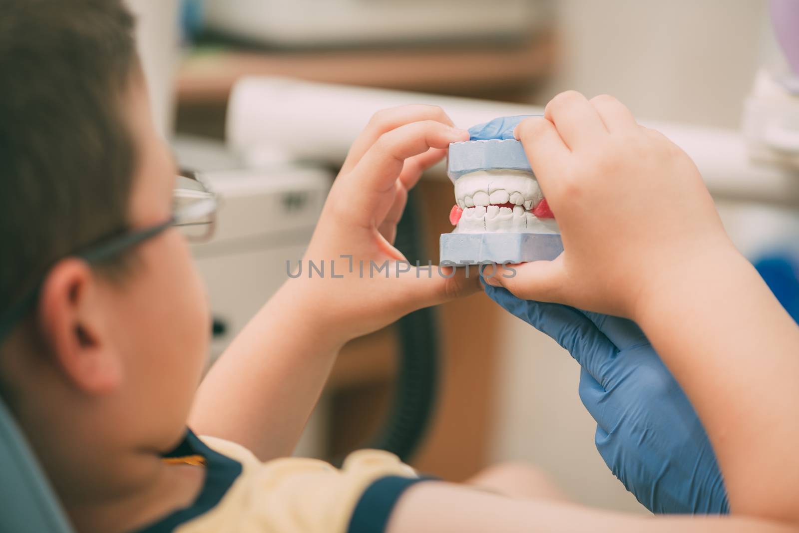 Dentist showing plaster cast jaws to the little boy patient. Selective focus. 