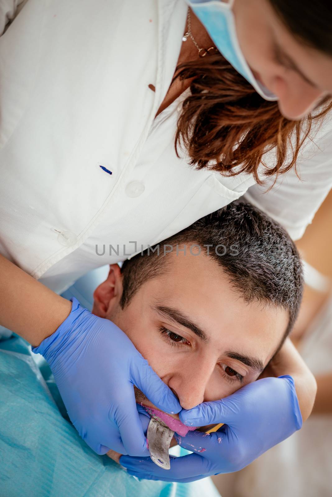 Dentist using dental impression for braces to the male patient. Real people.
