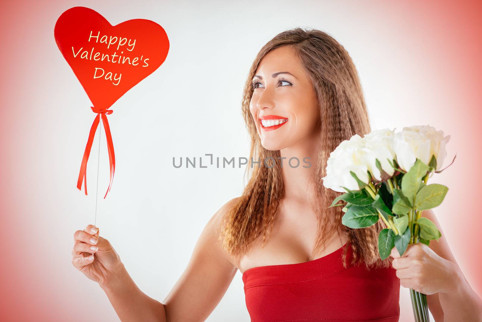 Portrait of a beautiful smiling girl holding a red heart and bouquet white roses.