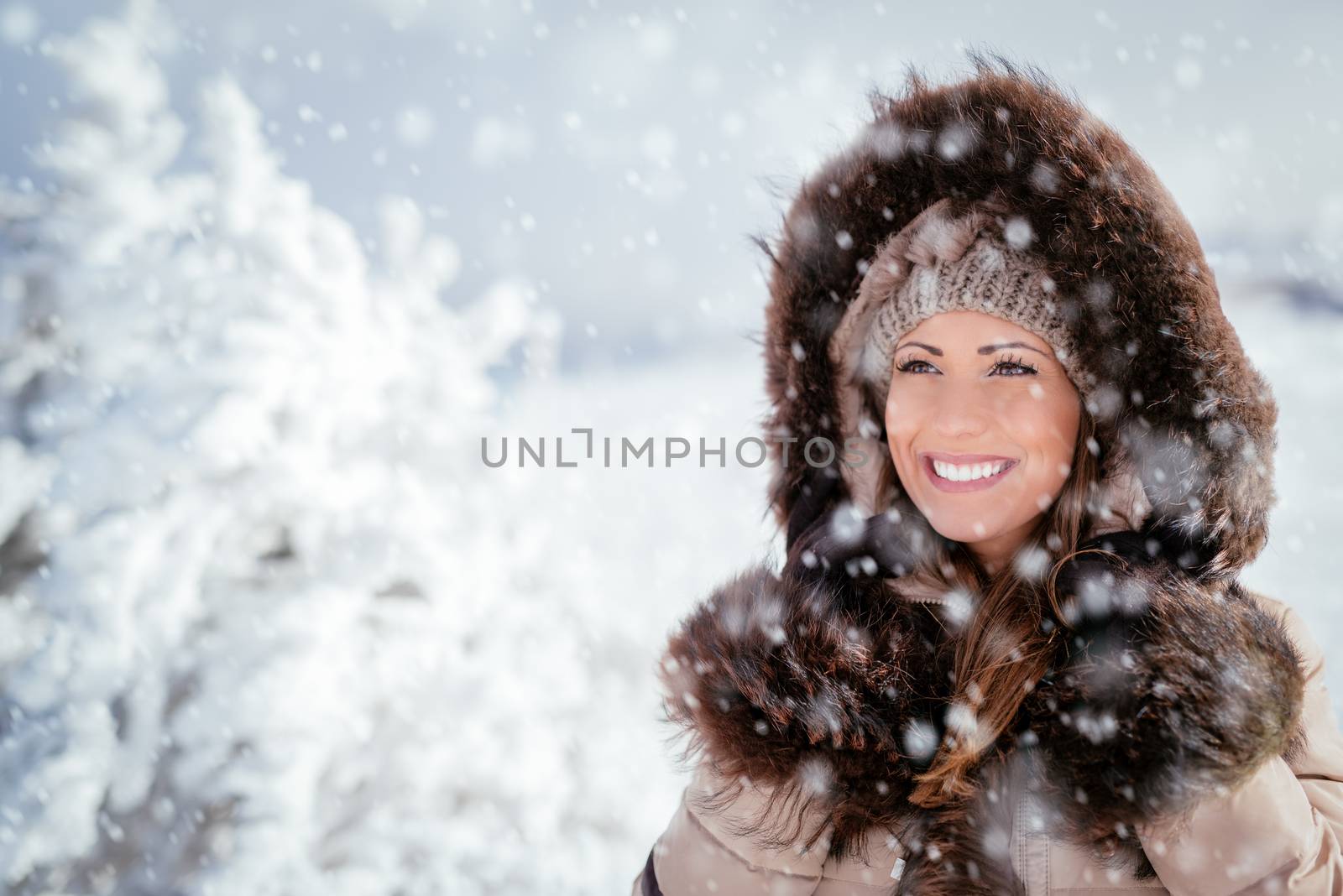 Portrait of a beautiful smiling girl outdoors while its snowing.