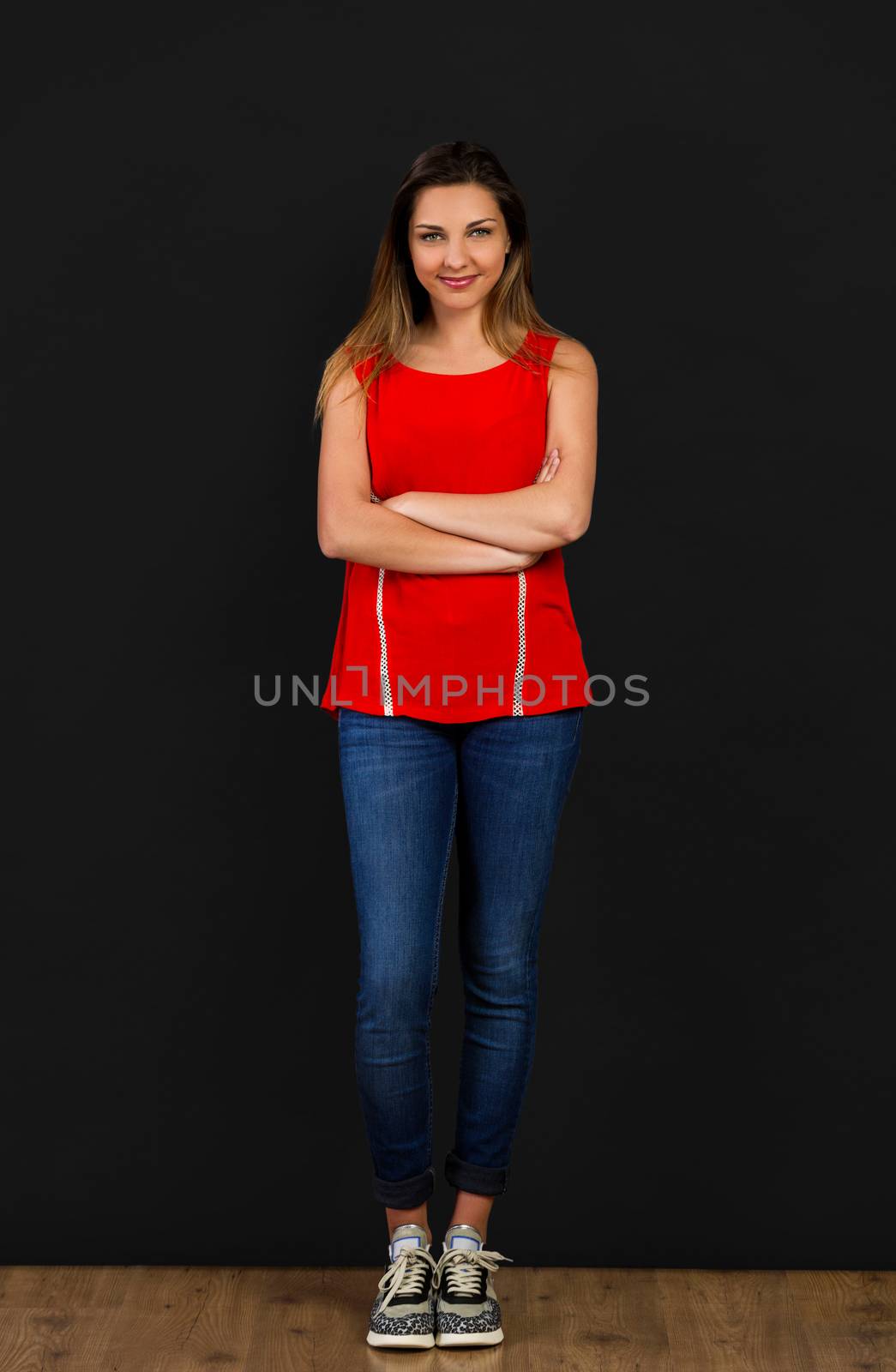 Beautiful woman with hands folded standing in front of a black wall