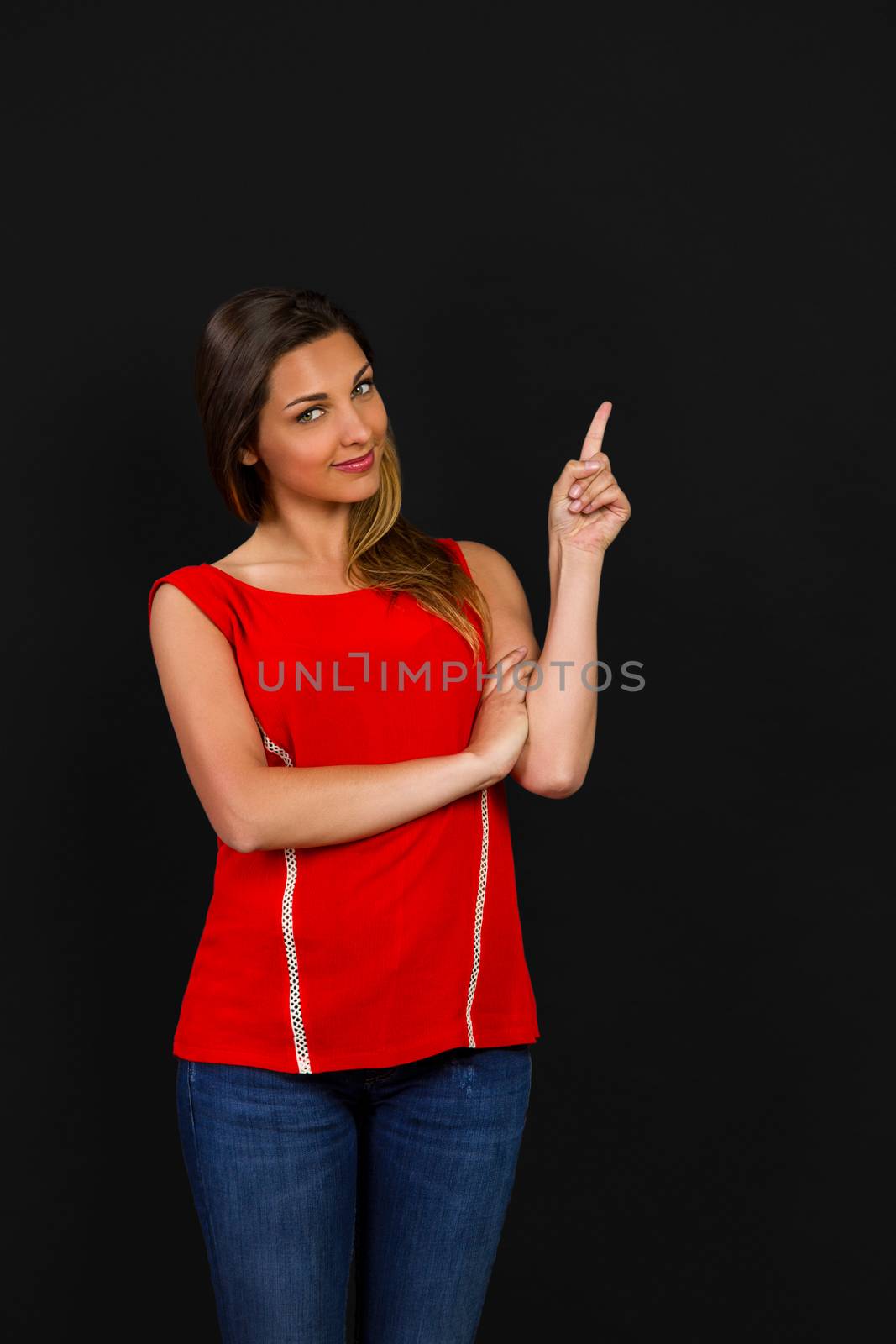 Beautiful woman standing in front of a dark board and pointing