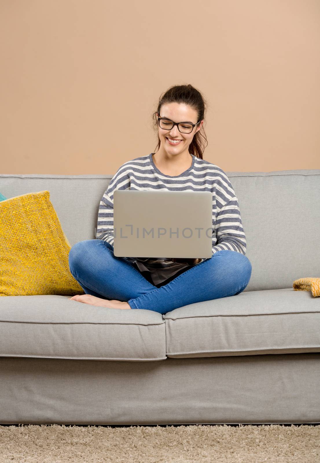 Beautiful woman at home sitting on the sofa and working with a laptop