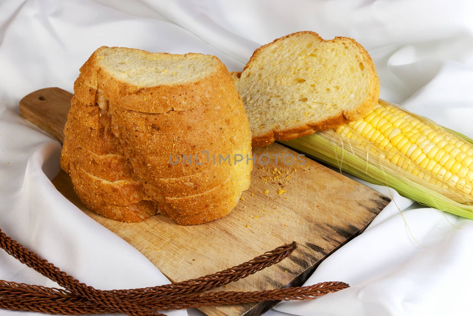 bread made from corn on the white fabric. Slices of corn bread laying on a chopping Board and Sweet corn cobs