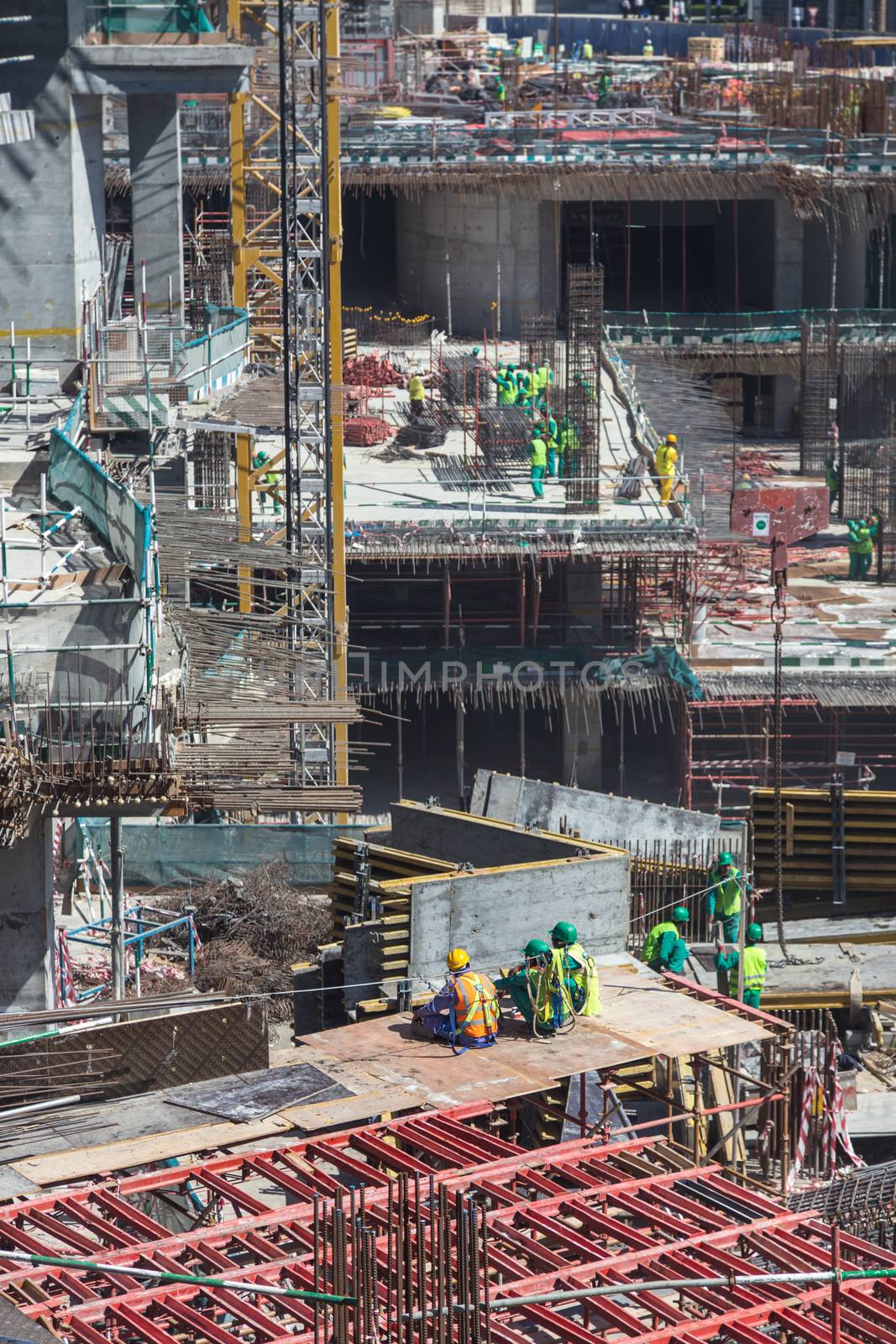 Laborers having a short break during work on modern constraction site works in Dubai. Fast urban development consept.