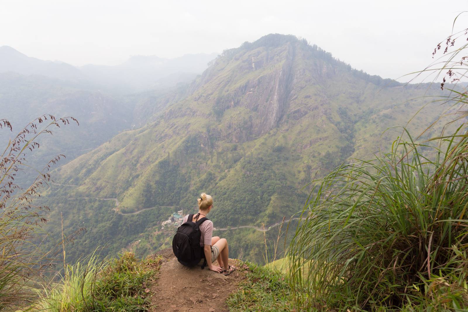 Woman enjoying pristine nature and beautiful view of tea plantations from the top of Small Adams peak near Ella, Sri Lanka. Tracking outdoors tourist adventure.