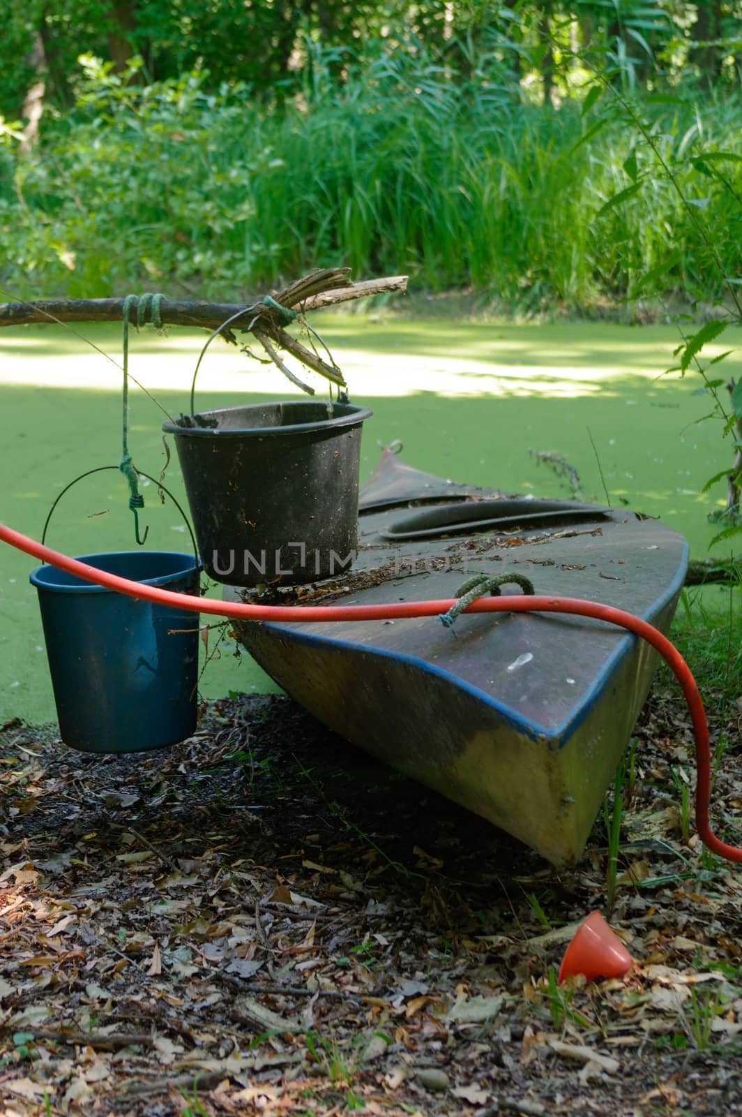 Old canoe ashore the pond with bucket on it by evolutionnow