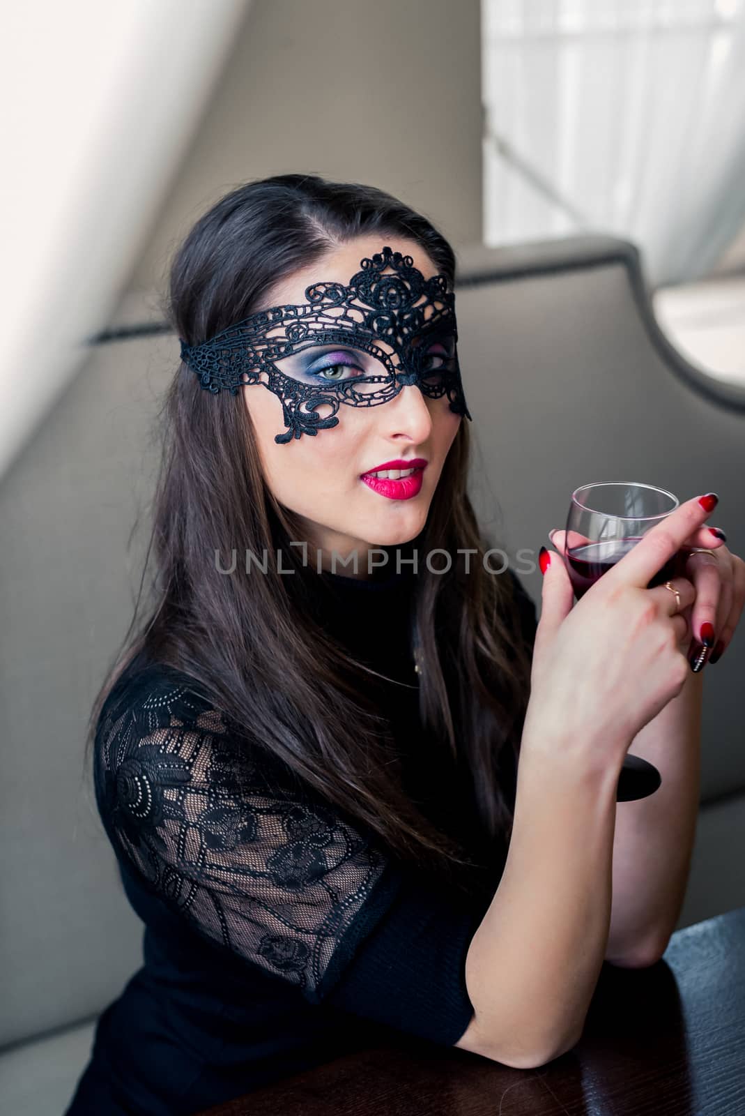 a beautiful girl sitting in the cafe with black mask and wine