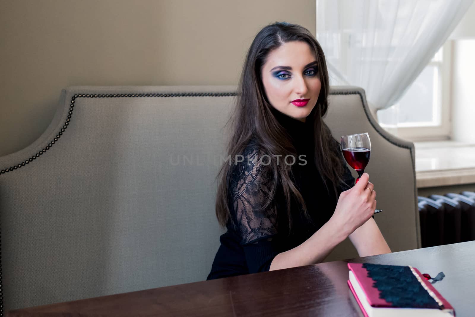 a beautiful girl sitting in the cafe with wine