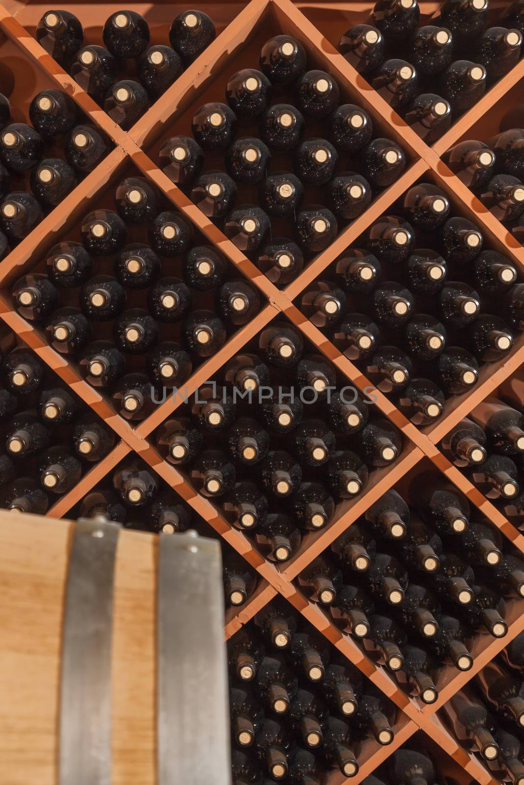 Several Varietal Wine Bottles and Barrel Age Inside Dark Cellar.