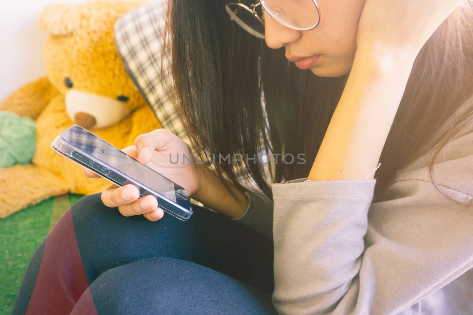 Woman typing text message on smart phone in a cafe. Cropped image of young woman sitting and using mobile phone.