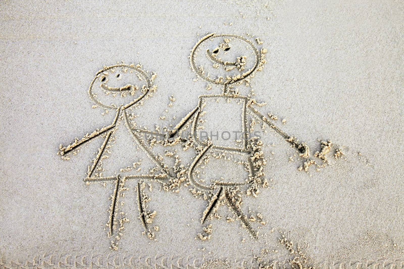 The child has drawn mum and daddy on sand