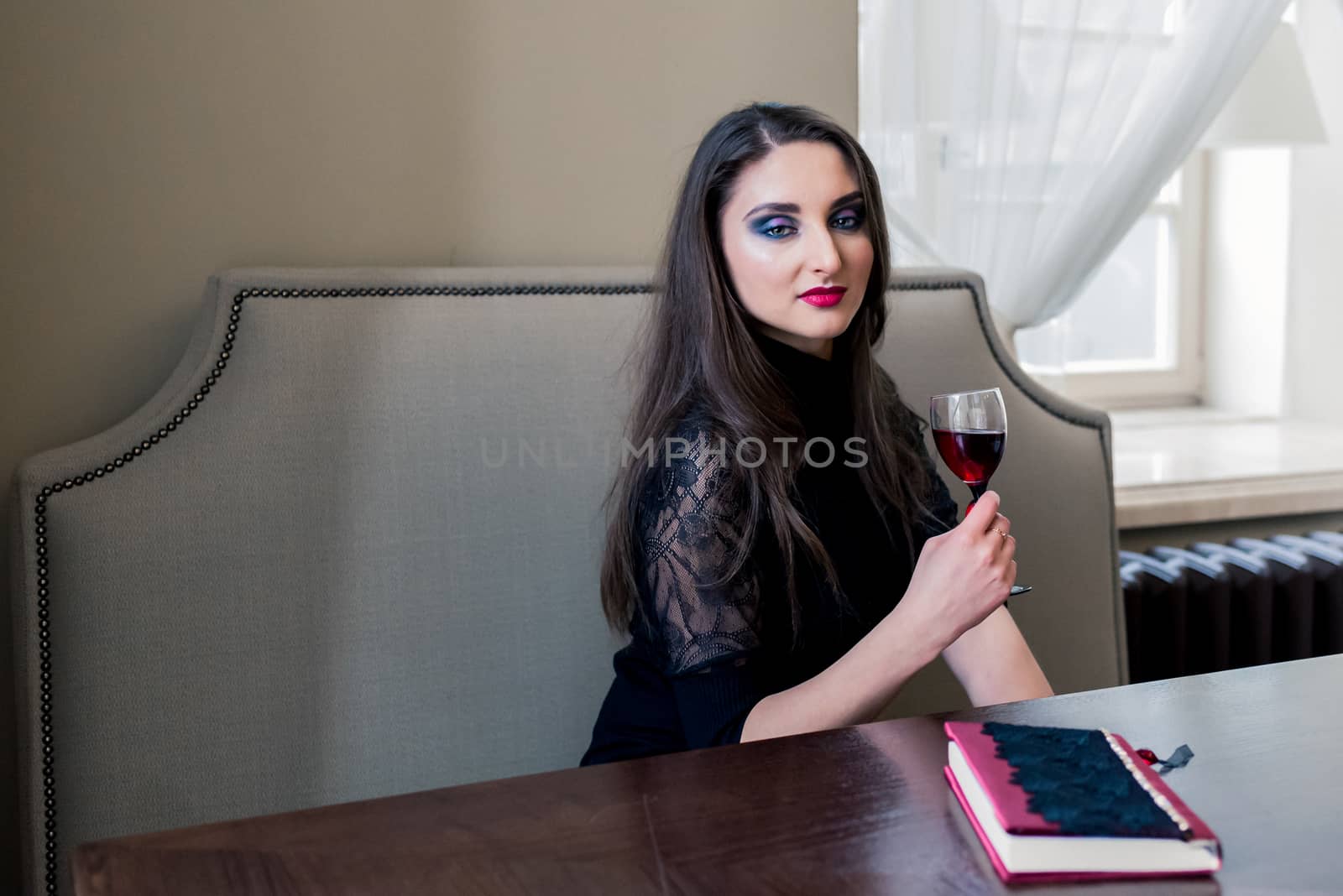 a beautiful girl sitting in the cafe with wine