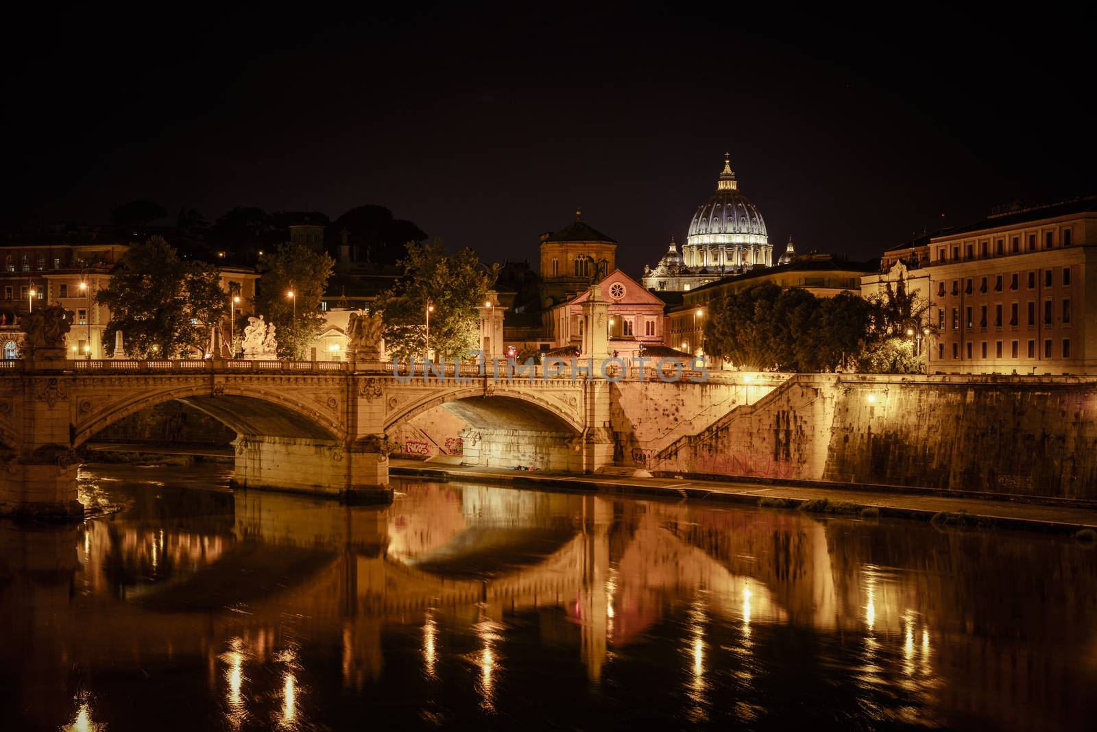 Basilica of San Pietro at night overlooking the Tevere river and surrounding historical landmarks of Rome.