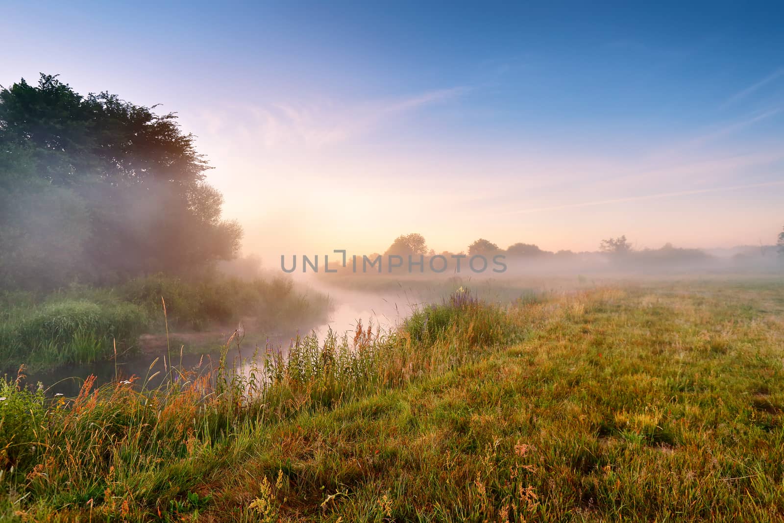 Summer misty sunrise on the river. Foggy river in the morning. Summer misty dawn. Foggy morning.