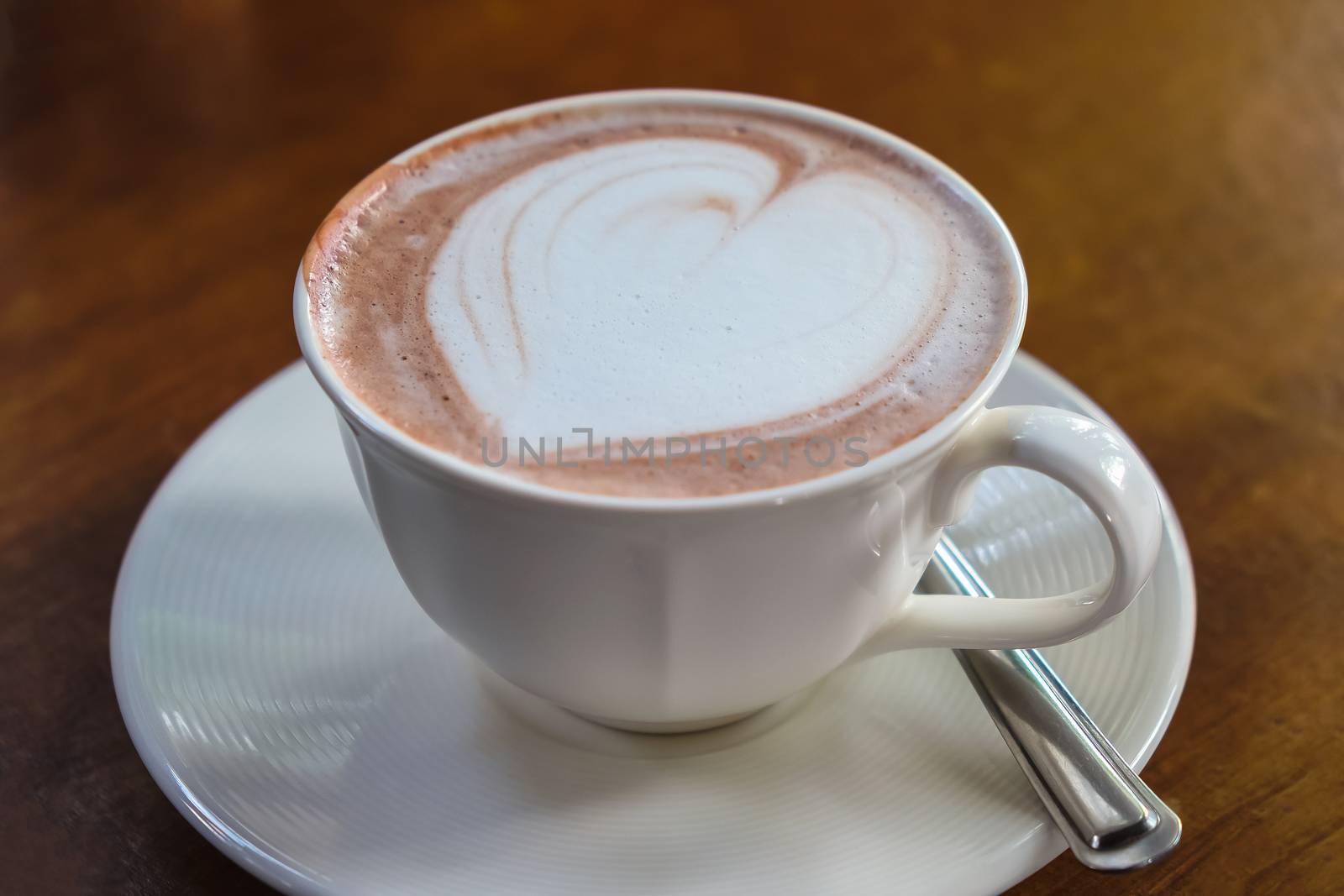 cup of hot latte art coffee on wooden table by luckyfim