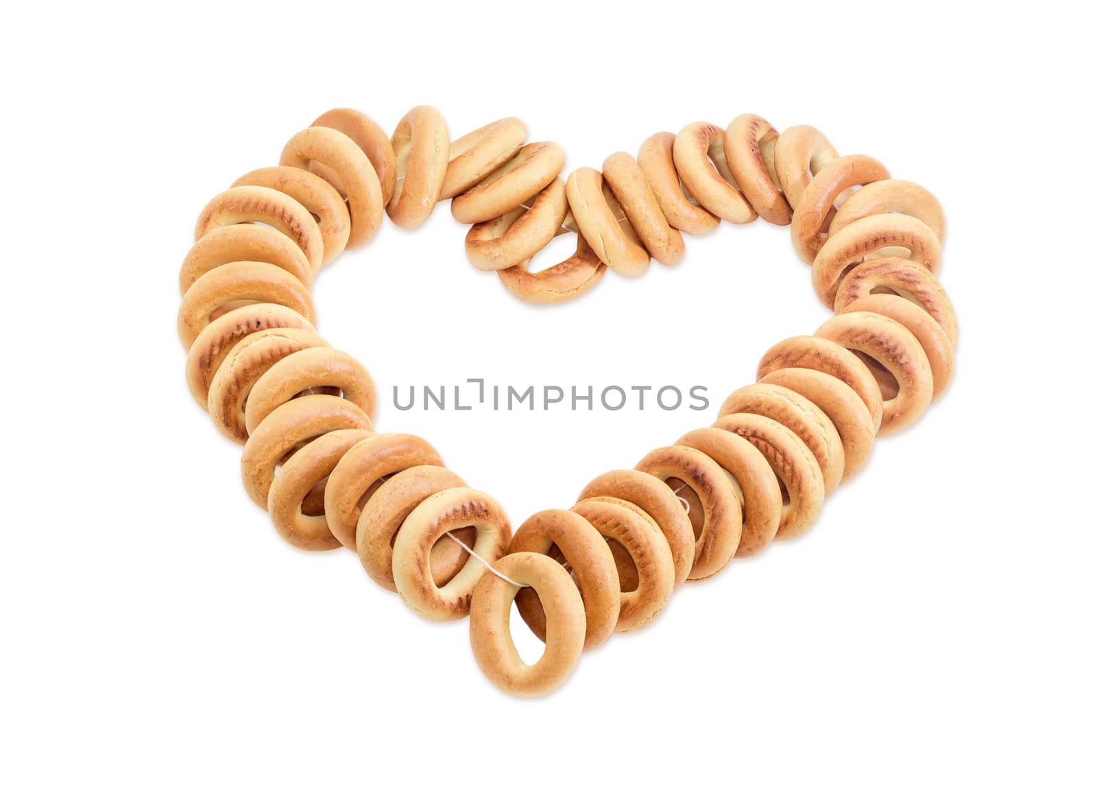 Bunch of small round bagels tied by cord and laid out in the form of heart on a light background 
