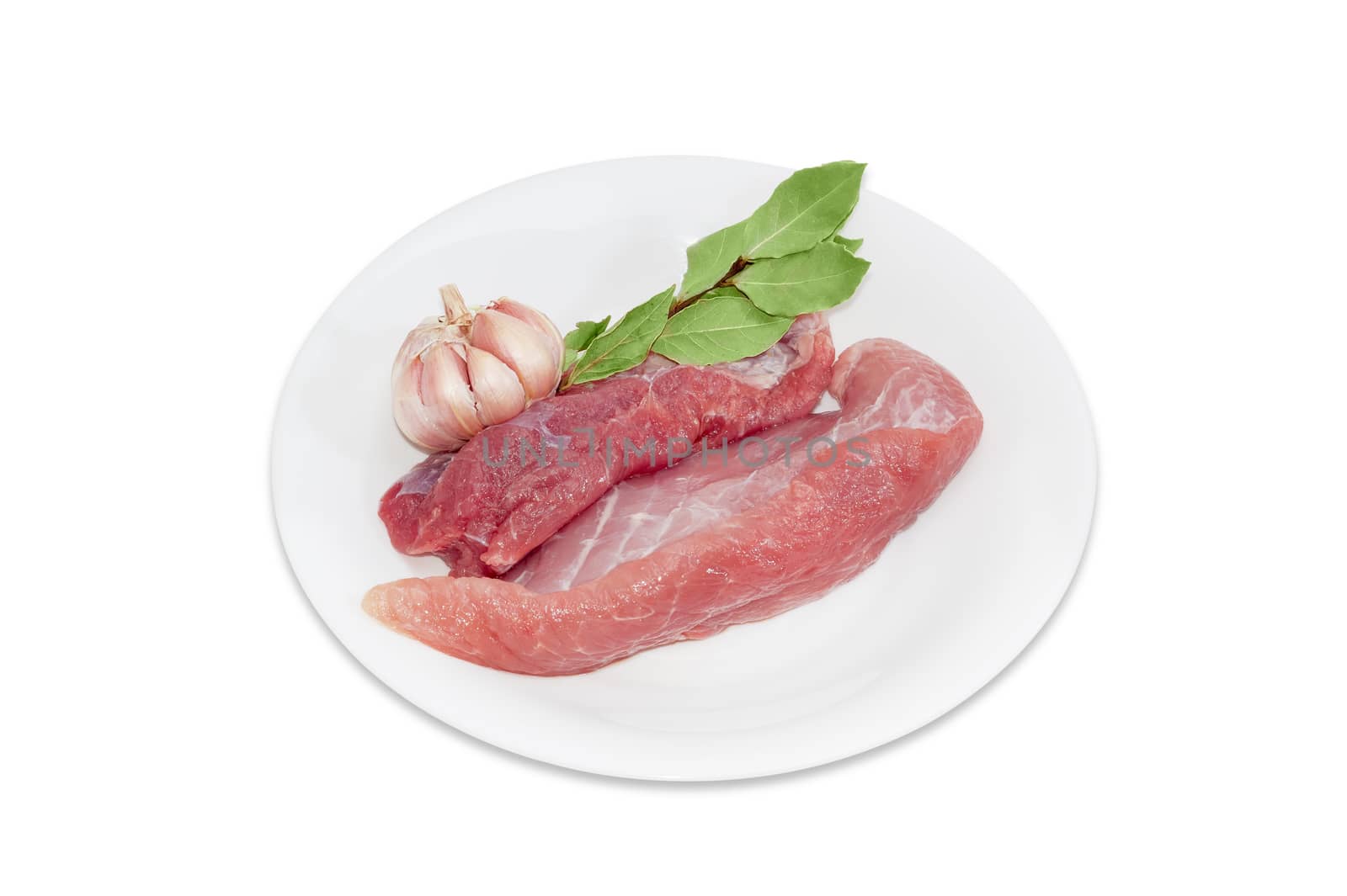 Several pieces of a fresh uncooked pork, branch of dried bay leaves and garlic on white plate on a light background 
