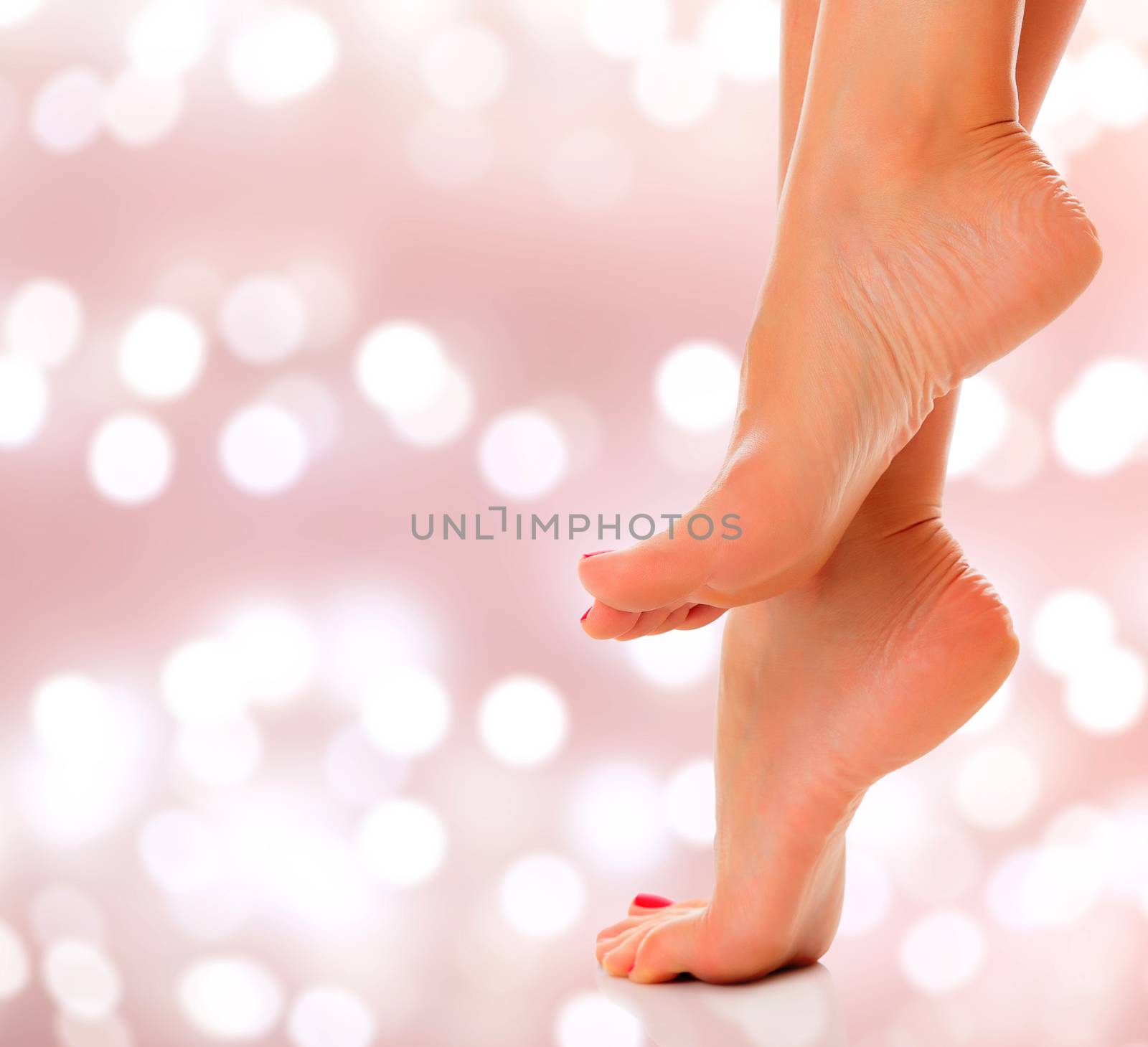 Woman feet closeup on an abstract background with blurred lights by Nobilior